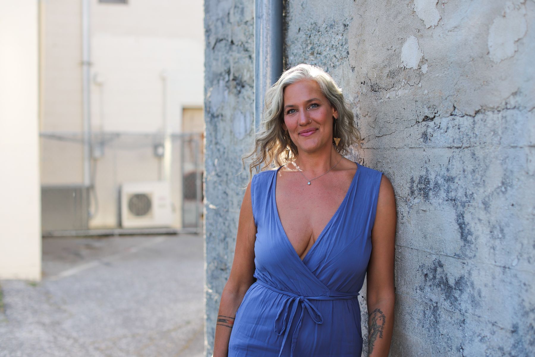 Alexis leaning in a blue dress, intimate interior light