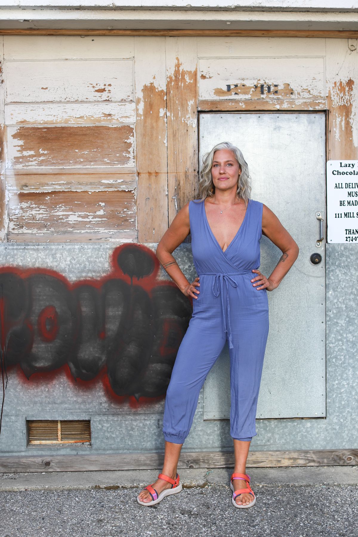 Alexis in a deep blue dress beside a dark wooden door, photographed by Kat Bacchus